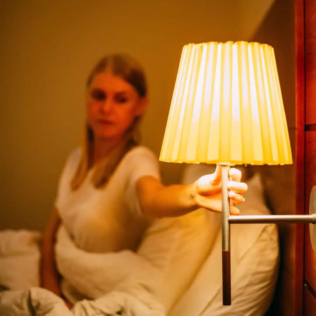 Fiatal nő alváshoz készülődik és éppen leoltja a lámpát