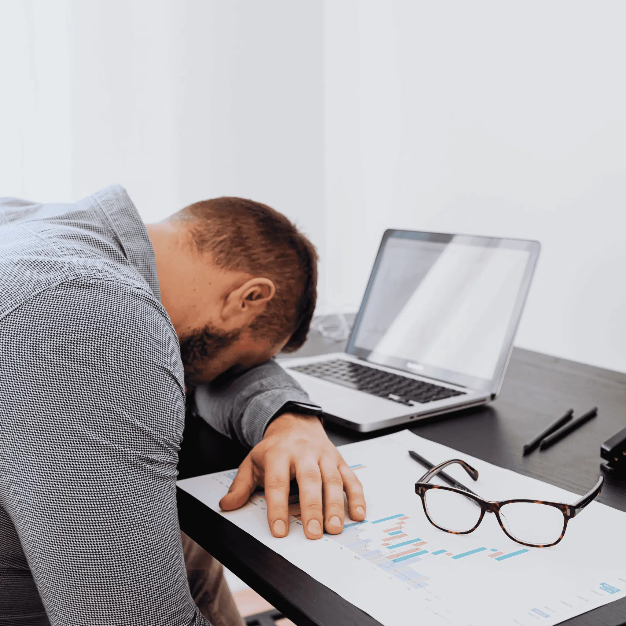 Fáradt férfi irodai környezetben - az alváshiány jelei munka közben.