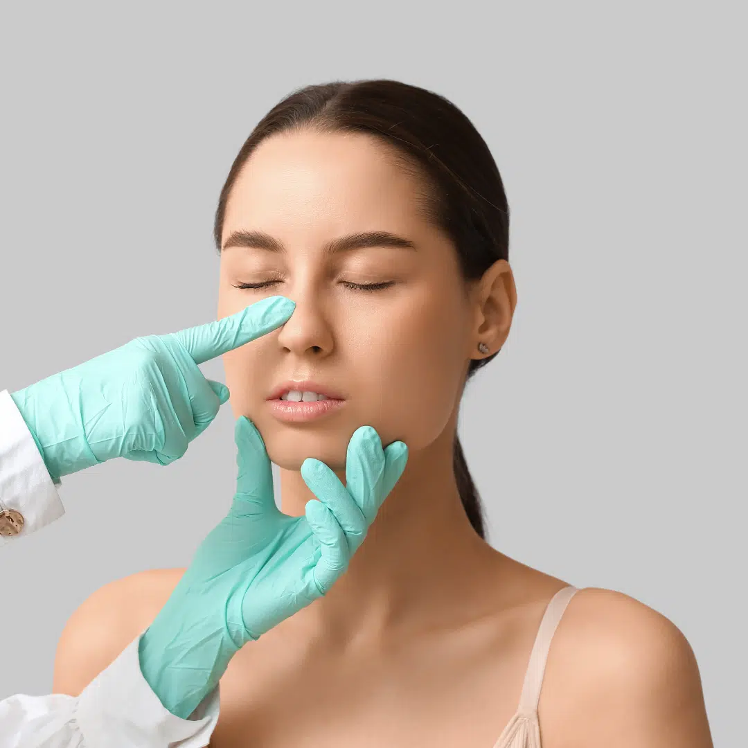 Egy fiatal nő orrát vizsgálja egy orvos. Az orvos egyik keze az orrnyerget tapintja, a másik a nő állát támasztja meg.